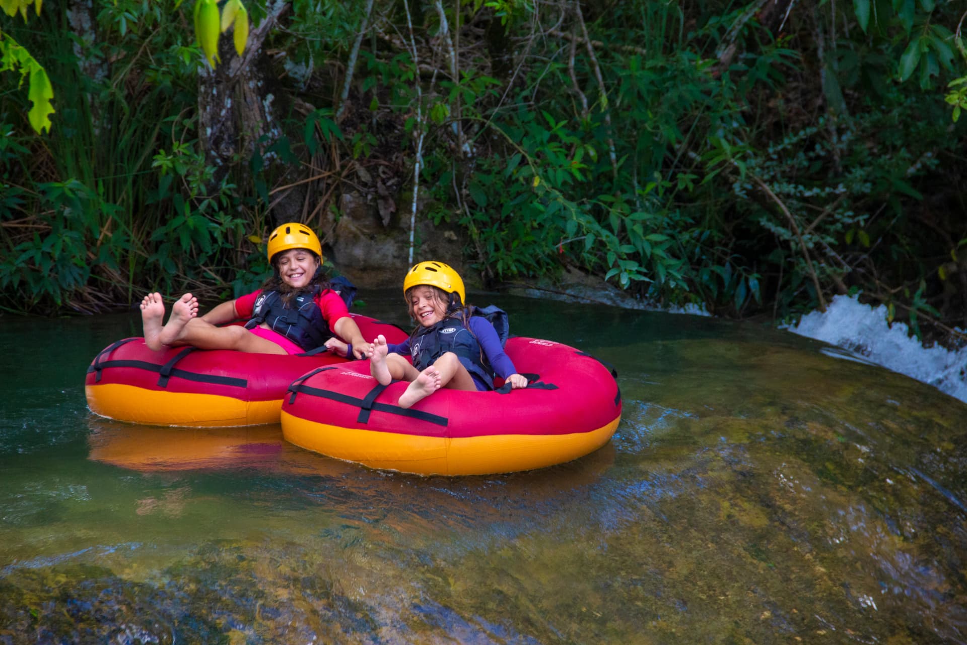 Duas crianças de capacete descendo o rio em boias no Parque Ecológico em Bonito